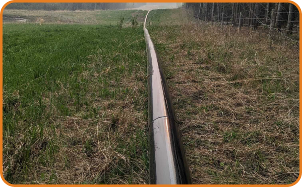 Above-ground black pipeline laid across grassy field for temporary bypass solution